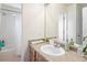 Bathroom featuring a single sink, light wood cabinets, framed mirror, and a shower-tub with patterned curtain at 8335 Deframe Ct, Arvada, CO 80005