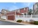 Exterior view of a two-story house featuring a private garage, white fence and beautiful landscaping at 8335 Deframe Ct, Arvada, CO 80005