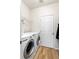 Functional laundry room with washer, dryer, shelving, and wood floors at 8335 Deframe Ct, Arvada, CO 80005