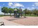 Community playground with slides and climbing structures surrounded by mature trees and grassy area at 8335 Deframe Ct, Arvada, CO 80005