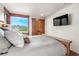 Bedroom with rustic wood doors, tv, and mountain view from window at 23 Verde Ct, Breckenridge, CO 80424