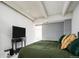 Well-lit bedroom includes ceiling beams, comfortable bed with reading spot and a TV stand at 675 S University Blvd # 106, Denver, CO 80209