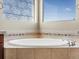 Close-up of a pristine white bathtub with chrome fixtures and decorative tile surround at 11545 S Flower Mound Way, Parker, CO 80134
