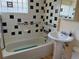 Bathroom with a tiled shower-tub combination, tiled black and white backsplash, and pedestal sink at 1337 Valentia St, Denver, CO 80220