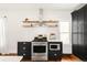 Charming kitchen with stainless steel appliances, modern cabinets, open wood shelving, and a subway tile backsplash at 3534 Decatur St, Denver, CO 80211