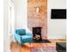 Bright living room with exposed brick fireplace and comfortable blue armchair at 3534 Decatur St, Denver, CO 80211
