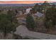 An aerial view shows a home surrounded by trees and a driveway leading to the garage with mountain views in the distance at 8258 W 66Th Dr, Arvada, CO 80004