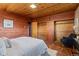 Bedroom featuring wood paneling, stone floors, built-in closets and neutral colored decor at 8258 W 66Th Dr, Arvada, CO 80004