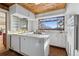 A retro kitchen design features white cabinets, a wood ceiling, vintage appliances, and abundant natural light at 8258 W 66Th Dr, Arvada, CO 80004