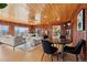 Open concept living room with wood paneled walls and large windows connects seamlessly with an adjacent dining area at 8258 W 66Th Dr, Arvada, CO 80004