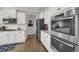 Well-equipped kitchen featuring stainless steel appliances, white cabinetry, and hardwood floors at 17052 Lipan St, Broomfield, CO 80023