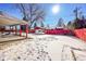 Large backyard with covered patio, storage shed, and snow covered ground at 12152 E Dakota Ave, Aurora, CO 80012