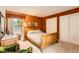 A cozy bedroom with an orange accent wall, light-colored carpet and a wooden sleigh bed at 9925 W Progress Pl, Littleton, CO 80123