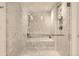 Luxurious walk-in shower with white marble tiling, rainfall showerhead, and a built-in ledge at 1750 Wewatta St # 704, Denver, CO 80202