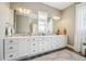 Bright bathroom featuring a double vanity with white cabinets, large mirrors, and modern lighting fixtures at 10151 E 138Th Pl, Brighton, CO 80602