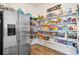 Well-stocked pantry with shelves full of groceries and a stainless steel refrigerator at 10151 E 138Th Pl, Brighton, CO 80602