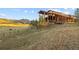 Stunning exterior of mountain home with natural wood facade, stone accents, and rolling hillside in the background at 6455 Dakota Ridge Dr, Golden, CO 80403