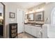 Bathroom with double sinks, granite counters, white cabinets, decorative mirrors, and modern fixtures at 6502 Shea Pl, Highlands Ranch, CO 80130