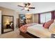 A bedroom features a large bed with red accents, a ceiling fan, a floor mirror, and a TV on a stand at 6502 Shea Pl, Highlands Ranch, CO 80130