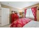 Comfortable bedroom with a vibrant red dresser, decorative textiles, and cozy chair at 6502 Shea Pl, Highlands Ranch, CO 80130