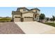Tan two story home featuring a 3-car garage, stone accents, and well-manicured landscaping at 42830 Ivydel St, Elizabeth, CO 80107