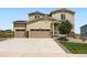 Tan two story home featuring a 3-car garage, stone accents, and well-manicured landscaping at 42830 Ivydel St, Elizabeth, CO 80107