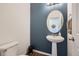 Stylish half bathroom with blue accent wall, pedestal sink, and neutral color scheme at 42830 Ivydel St, Elizabeth, CO 80107