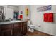 Well-lit bathroom featuring a single sink vanity, a toilet, and race themed wall decor with coordinating colors at 15460 Canyon Gulch Ln # 105, Englewood, CO 80112