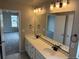 Bright bathroom featuring a double sink vanity, large mirror, and a view into the bedroom at 1759 Jennifer St, Brighton, CO 80601