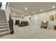 A spacious carpeted basement rec room with stairs, gray reclining sofa, and recessed lighting at 25059 E Alder Dr, Aurora, CO 80016