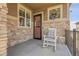 Inviting front porch features stone accents, a cozy rocking chair, and a decorative wreath on the window at 25059 E Alder Dr, Aurora, CO 80016