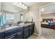 Double sink bathroom boasting granite countertops, dark cabinetry, and a view to the main bedroom at 4920 S Netherland Way, Centennial, CO 80015