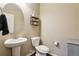 Well-lit powder room with a pedestal sink, round mirror and decorative shelving at 4920 S Netherland Way, Centennial, CO 80015