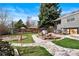 Beautifully landscaped backyard featuring a manicured lawn, stone pathway, water feature, and an outdoor dining area at 10629 W Glasgow Ave, Littleton, CO 80127