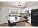 Bright kitchen featuring white cabinetry, a mosaic tile backsplash, a large island with wood countertop, and modern appliances at 10629 W Glasgow Ave, Littleton, CO 80127