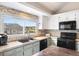 Bright kitchen featuring white cabinetry, a mosaic tile backsplash, a large island with wood countertop, and modern appliances at 10629 W Glasgow Ave, Littleton, CO 80127