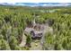 Aerial view of a home with a large deck surrounded by lush forest at 24 Navajo Trl, Evergreen, CO 80439