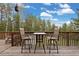 An outdoor balcony with high-top furniture and a view of the surrounding trees at 24 Navajo Trl, Evergreen, CO 80439