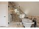 Bright bathroom featuring a bathtub, glass shower and textured stone wall at 24 Navajo Trl, Evergreen, CO 80439