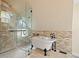 Elegant bathroom boasts a clawfoot tub, tiled shower with glass enclosure, and natural stone accents at 24 Navajo Trl, Evergreen, CO 80439