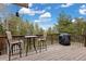 Inviting deck with outdoor seating and grill, surrounded by lush greenery and serene views at 24 Navajo Trl, Evergreen, CO 80439