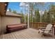 Wooden deck with a hot tub, chair, and view of the surrounding trees at 24 Navajo Trl, Evergreen, CO 80439