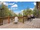 Relaxing deck with chairs, grill, and views of the surrounding pine trees at 24 Navajo Trl, Evergreen, CO 80439