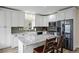 Bright kitchen features white cabinetry, stainless steel appliances, and a gray backsplash, plus a granite island with bar seating at 24 Navajo Trl, Evergreen, CO 80439