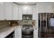 Bright kitchen featuring stainless steel appliances, white cabinets, gray backsplash, and stone countertops at 24 Navajo Trl, Evergreen, CO 80439