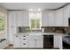 Bright kitchen with white cabinets, a farmhouse sink, stainless appliances, stone countertops, and views of the landscape at 24 Navajo Trl, Evergreen, CO 80439