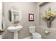 Elegant half bathroom features a pedestal sink, toilet, and decorative niche with flower arrangement at 6690 S Fenton St, Littleton, CO 80123
