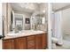 Well-lit bathroom featuring double sinks, wood cabinets, and a shower with neutral, tiled walls at 6690 S Fenton St, Littleton, CO 80123
