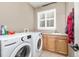 Functional laundry room equipped with modern washer, dryer, utility sink and storage cabinets at 6690 S Fenton St, Littleton, CO 80123