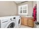 Functional laundry room with a washer, dryer, utility sink, and cabinet storage underneath at 6690 S Fenton St, Littleton, CO 80123